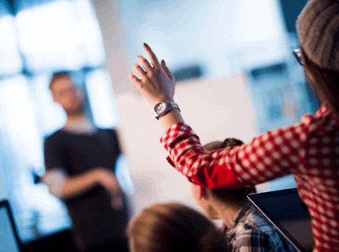 Woman with hand raised asking a question.
